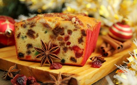Traditionnal fruit cake for christmas with anise, cinamon and dried cranderries with christmas background